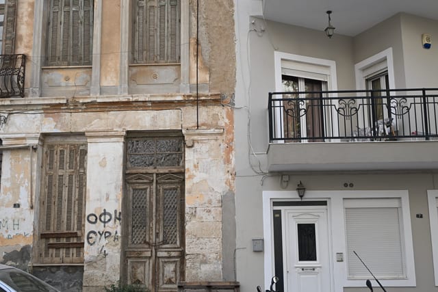 Faded apartment building with peeling paint stands next to a renovated whitewashed rental facade