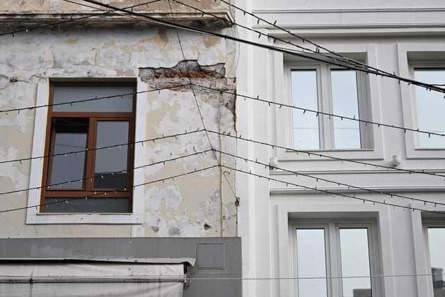 Rusted metal railing on a balcony next to a sleek modern window installation