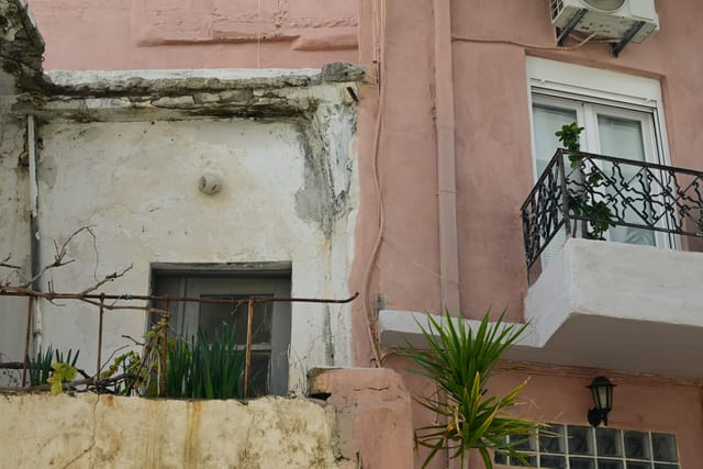 Two adjacent buildings showing the stark contrast between decay and renovation
