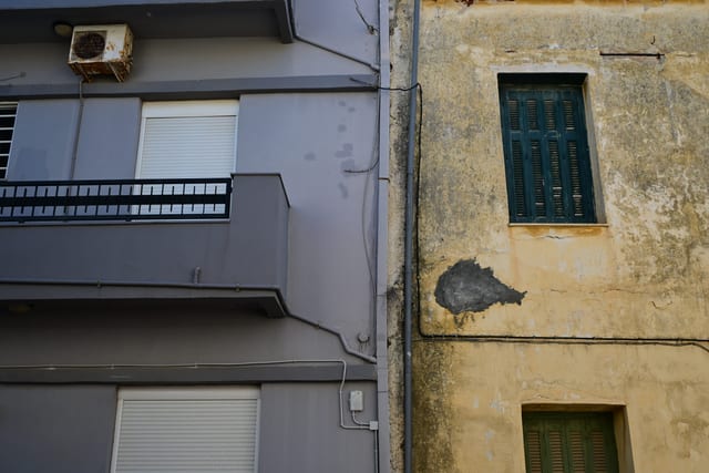 Face of a building with peeling paint and new double-glazed windows